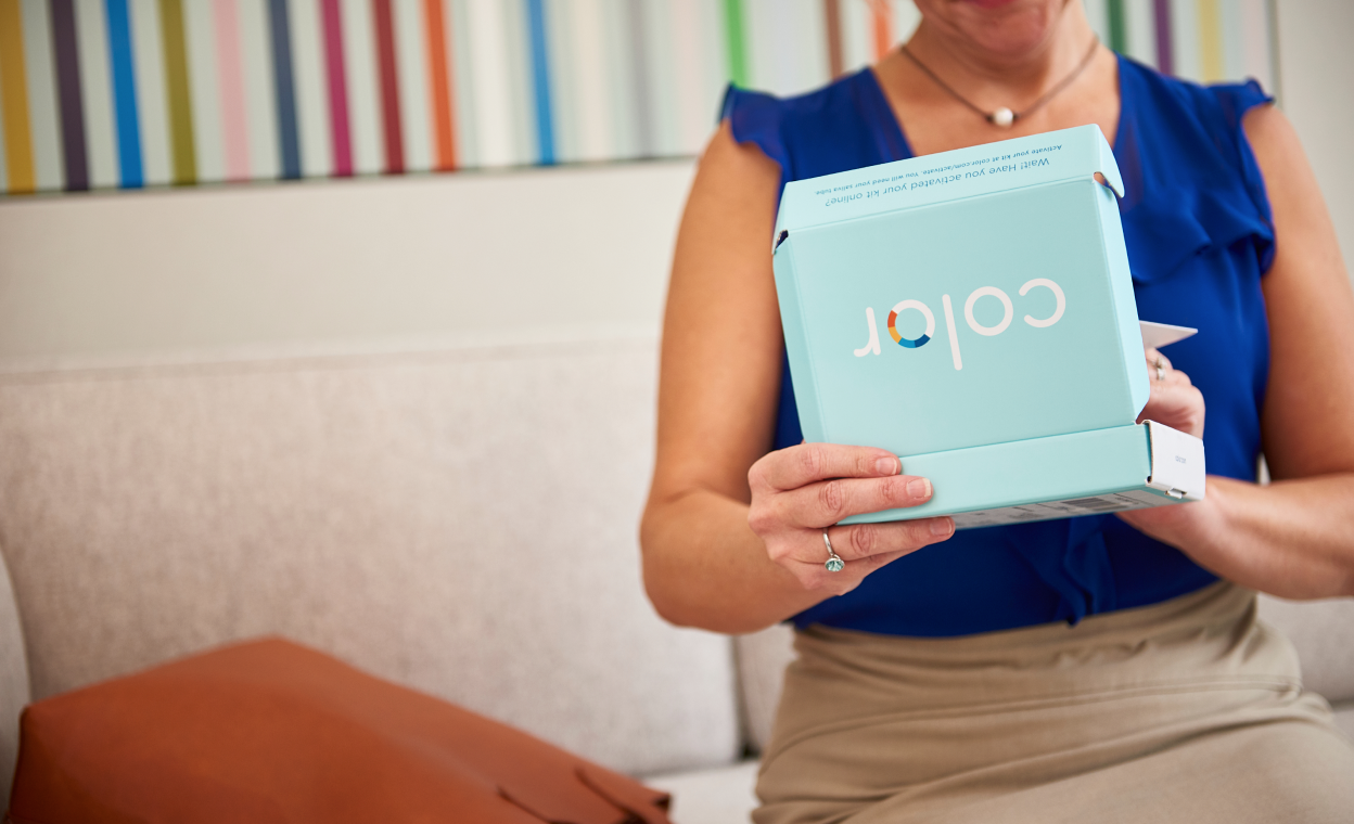 Woman sitting on a coach holding a light blue Color test kit